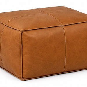 May include: A rectangular ottoman upholstered in a smooth, tan-coloured material with a leather-like texture. The piece features prominent piped edges and a cross-stitched seam pattern across the top surface, creating a structured, boxy silhouette.