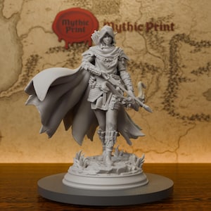 Könnte beinhalten: Eine graue Harz-Miniaturfigur eines Elfen-Bogenschützen mit Kapuzenumhang, texturierter Rüstung und Stiefeln. Die Figur steht auf einem felsigen Sockel, hält eine Armbrust und einen Köcher, mit dem sichtbaren Schriftzug Mythic Print.