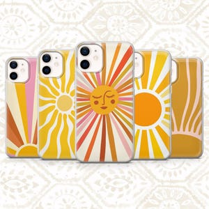 May include: Five clear phone cases featuring various sun-themed designs. The patterns include radiating sunbeams in shades of yellow, orange, pink, and cream, with one central sun graphic displaying a stylized face with closed eyes and eyelashes.