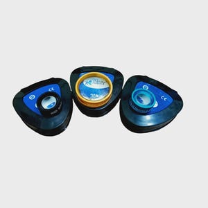 Puede incluir: Tres lentes de diagn&oacute;stico oft&aacute;lmico montadas sobre bases triangulares negras. La lente izquierda es negra marcada 90D, la central es dorada marcada 30D y la derecha es azul verdoso marcada 20D DOUBLE. Cada base tiene un inserto azul con marca CE.