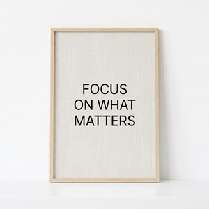 Op de afbeelding: Een rechthoekige wandkunstprint in een lichthouten lijst met een getextureerde gebroken witte achtergrond en de zwarte tekst FOCUS ON WHAT MATTERS in het midden. Het ontwerp is strak en eenvoudig met een verticale oriëntatie en duidelijke typografie.