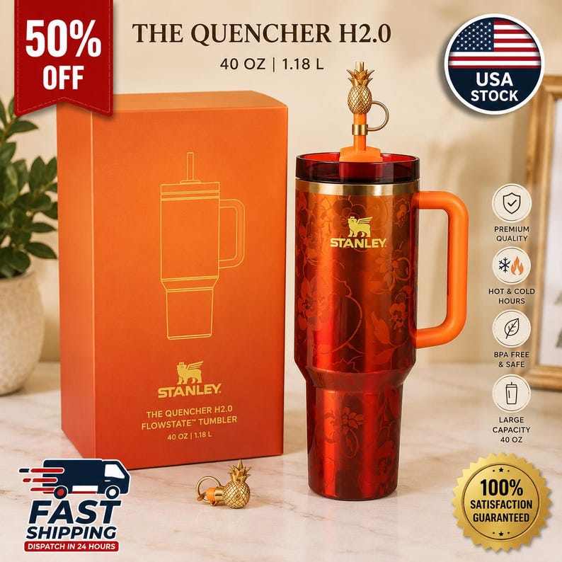 May include: A red Stanley Quencher H2.0 FlowState tumbler with a 40 oz capacity, featuring a floral pattern, a side handle, and a gold pineapple-shaped straw topper. The tumbler is displayed next to its matching orange product box.