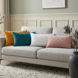 Può includere: Quattro cuscini rettangolari disposti su un divano grigio chiaro. I cuscini presentano un motivo a rombi trapuntato e sono di colore giallo senape, verde ottanio, bianco e rosa antico. Ogni cuscino ha una consistenza morbida.