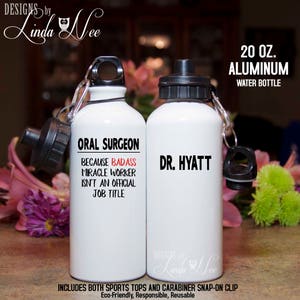 Puede incluir: Dos botellas de agua de aluminio blanco de 20 onzas con tapas negras y asas de transporte. Una botella dice "Cirujano oral porque el trabajador milagroso rudo no es un título de trabajo oficial" y la otra botella dice "Dr. Hyatt".
