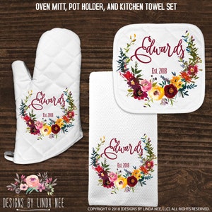 May include: A set of three kitchen items featuring a floral wreath design with the text "Edwards Est. 2018". The set includes an oven mitt, a pot holder, and a kitchen towel.
