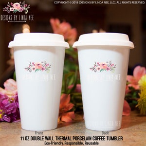 May include: Two white 11 oz double-wall thermal porcelain coffee tumblers with white lids. Each tumbler features a floral design and the text "DESIGNS BY LINDA NEE". The text "Front" and "Back" are visible. The tumblers are eco-friendly and reusable.