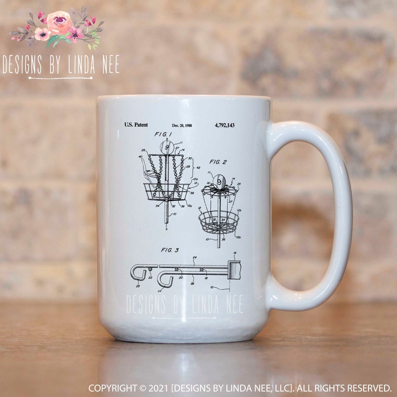 May include: White ceramic mug featuring a black and white diagram of a disc golf basket, with the text "U.S. Patent" and "Dec. 28, 1988". The mug also has the text "DESIGNS BY LINDA NEE" and "COPYRIGHT &copy; 2021 [DESIGNS BY LINDA NEE, LLC]. ALL RIGHTS RESERVED."