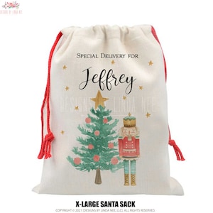 Könnte beinhalten: Eine weiße Stofftasche mit einem roten Kordelzug. Die Tasche hat eine Aquarell-Illustration eines Weihnachtsbaums mit Kugeln und einem Nussknacker. Der Text "SPECIAL DELIVERY FOR Jeffrey" ist auf der Tasche aufgedruckt.