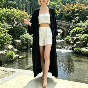 May include: A long, black open-front robe with wide sleeves, paired with a white strapless tube top and matching white shorts. The ensemble features a simple, solid-colored design with a relaxed fit, showcasing a coordinated two-piece set layered under a lightweight, floor-length outer garment.