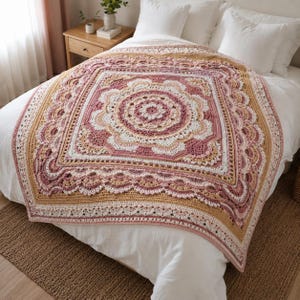 May include: A square crochet blanket featuring a central mandala pattern in shades of dusty rose, cream, and muted gold. The design incorporates intricate textured stitches, including popcorn and shell motifs, arranged in concentric layers.