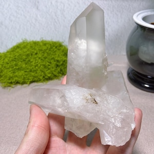 May include: A clear, multi-pointed quartz crystal cluster featuring a tall, vertical primary point and a horizontal secondary point. The mineral specimen displays translucent and opaque white sections with natural internal fractures and inclusions.