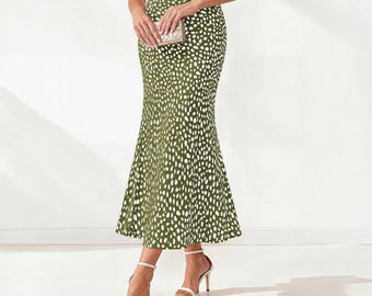 Puede incluir: Una falda midi de talle alto en color verde oliva con un estampado animal de motas blancas. La falda tiene una silueta ajustada en las caderas y los muslos que se ensancha ligeramente hacia el dobladillo, creando una forma de sirena.