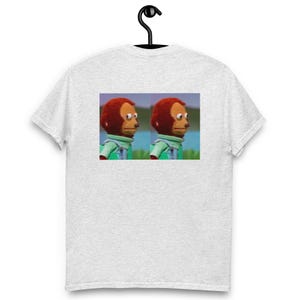 Peut inclure: T-shirt gris clair avec un mème de deux marionnettes singes regardant de côté. Les marionnettes ont des poils bruns, des yeux blancs et portent des chemises vertes et des gilets bleus. L'image est centrée sur le devant du t-shirt.
