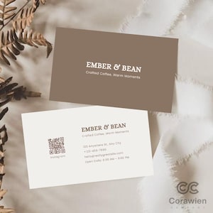 Könnte beinhalten: Zwei rechteckige Visitenkarten für Ember & Bean. Eine Karte ist braun mit weißem Text, der Ember & Bean, Crafted Coffee, Warm Moments lautet. Die andere ist cremefarben mit braunem Text, einem QR-Code und Kontaktdaten.