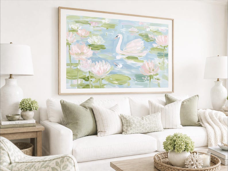May include: A large rectangular wall art print in a light wood frame featuring an impressionistic painting of a white swan swimming in a pond filled with pink water lilies and green lily pads, set against a soft blue and white water background.