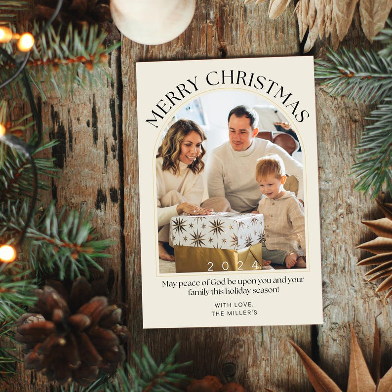 Puede incluir: Una tarjeta de Navidad con una foto de una familia de tres abriendo un regalo. La tarjeta tiene un arco dorado con el texto "Merry Christmas" y el a&ntilde;o "2024". El texto "May peace of God be upon you and your family this holiday season! With love, The Miller's" est&aacute; impreso debajo de la foto.