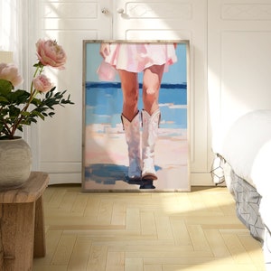 K&ouml;nnte beinhalten: Ein Gem&auml;lde einer Frau in einem rosa Kleid und wei&szlig;en Cowboystiefeln, die auf einem Strand mit blauem Wasser im Hintergrund steht.