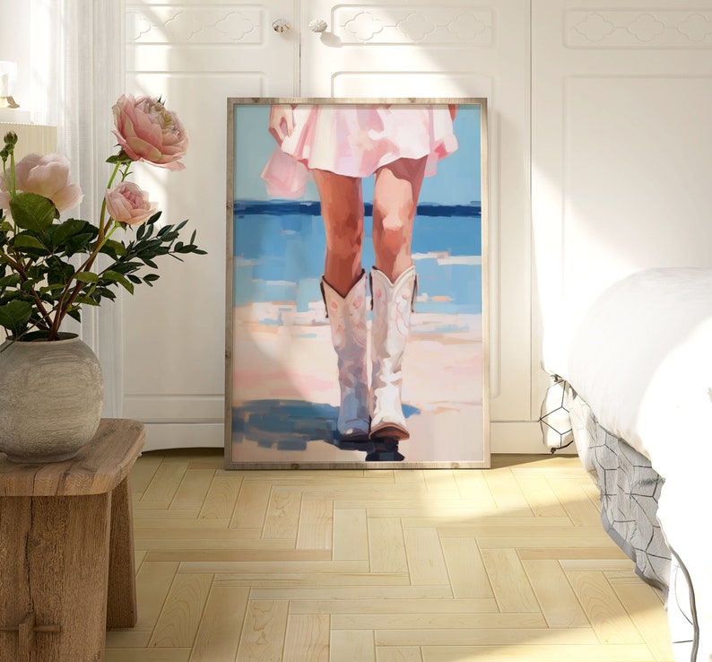 K&ouml;nnte beinhalten: Ein Gem&auml;lde einer Frau in einem rosa Kleid und wei&szlig;en Cowboystiefeln, die auf einem Strand mit blauem Wasser im Hintergrund steht.