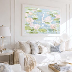 May include: A framed wall art print featuring a white swan swimming in a pond filled with light pink lotus flowers and green lily pads. The painting uses soft brushstrokes in shades of blue, white, and pink to depict a serene water scene.