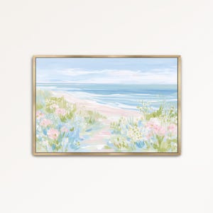 May include: A horizontal landscape painting in a gold frame depicting a coastal scene with a sandy beach, blue ocean waves, and a pale sky. The foreground features soft, painterly clusters of pink and white flowers with green foliage.