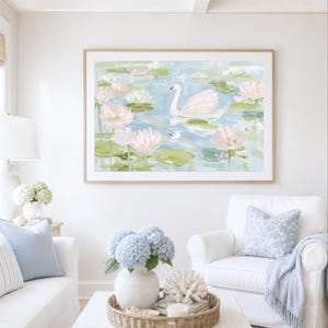 May include: A framed horizontal wall art print featuring an impressionistic painting of a white swan swimming in a pond filled with light pink water lilies and green lily pads, rendered in soft pastel tones of blue, green, and white.