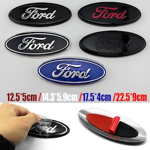 Könnte beinhalten: Ovale Ford-Embleme in Schwarz, Rot, Weiß und Blau. Das Bild zeigt verschiedene Embleme mit dem Ford-Logo, mit Größenangaben in Zentimetern. Bei einem Emblem wird eine Schutzfolie abgezogen.