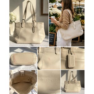 May include: A cream-colored leather tote bag featuring dual shoulder straps with buckle adjustments, a rectangular base, and a hanging leather luggage tag. The interior is lined with fabric and includes a serial number embossed as No L6C 4257.