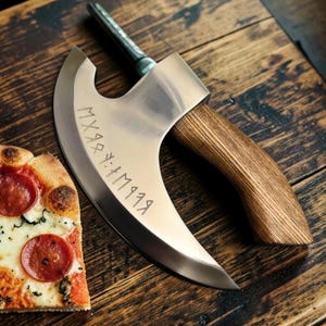 May include: A silver-coloured metal pizza cutter with a curved blade and a wooden handle. The blade features engraved runic-style characters. A slice of pepperoni pizza with melted cheese and tomato sauce is positioned next to the cutter.