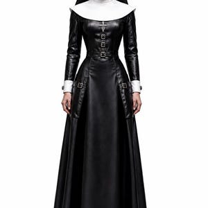 Pode incluir: Um vestido preto até ao chão com mangas compridas, punhos brancos e gola branca. O vestido apresenta um corpete justo com fivelas prateadas, um cinto na cintura e uma saia larga. Um toucado preto e branco completa o conjunto.