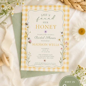 May include: A rectangular bridal shower invitation card with a yellow and white gingham border, featuring floral illustrations, bees, and the text: She's found her honey, Please join us for a Bridal Shower honoring Madison Wells, Saturday, July 18.