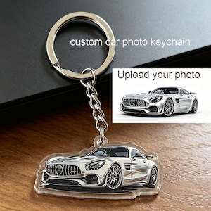 May include: A silver-colored metal keychain featuring a circular ring and a chain attached to a clear acrylic pendant. The pendant displays a printed image of a silver sports car. The text "custom car photo keychain" and "Upload your photo" appear.