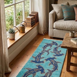 May include: A rectangular area rug featuring a vibrant turquoise background with a repeating pattern of dark blue hammerhead sharks. The rug has a textured pile and is finished with short white fringe along both of the shorter ends.