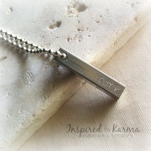 May include: Silver necklace with a silver bar pendant that says "DUTY".