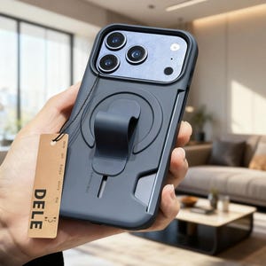 Op de afbeelding: Een donkergrijze telefoonhoes met een ingebouwde standaard en een label met de tekst "DELE". De hoes heeft een strak ontwerp, een camera-uitsparing en een magnetische ring. Het label luidt "Wish you happy every day".