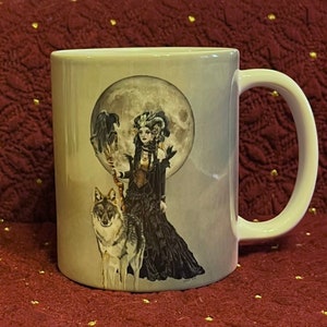 以下が含まれることがあります： 白磁のマグカップに、黒と白のイラストで描かれた、狼と女性の絵が描かれています。女性は黒いドレスを着て、王冠をかぶっています。狼は彼女の隣に立っています。背景は灰色の月です。