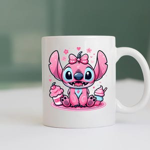 K&ouml;nnte beinhalten: Ein wei&szlig;er Keramikbecher mit einer bunten Grafik eines rosa Alien-Charakters mit gro&szlig;en Ohren und einer Schleife auf dem Kopf. Die Figur sitzt auf einer runden rosa Matte, flankiert von einem rosa Cupcake und einem blau-rosa Dessert mit Strohhalm.