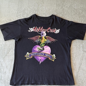 以下が含まれることがあります： Mötley CrüeとWITHOUT YOUの文字がプリントされた黒の半袖Tシャツ。胸の中央には、紫色のハート、緑色のヘビ、翼のあるドクロ、そして帯状のバナーに乗った小さな人物が描かれたグラフィックデザインが施されています。