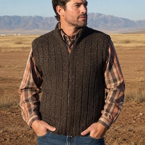 May include: A dark brown, ribbed knit vest featuring a full-length front zipper closure and a stand-up collar, worn over a long-sleeved, brown and tan plaid button-down shirt paired with classic blue denim jeans.