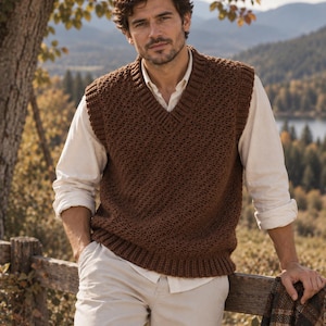 Può includere: Un gilet marrone senza maniche con scollo a V, caratterizzato da un motivo a maglia testurizzato con bordi a coste su scollo, giromanica e orlo, indossato sopra una camicia bianca a maniche lunghe e pantaloni di colore chiaro.