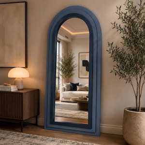 Peut inclure: Un grand miroir sur pied avec un sommet en arche et un cadre bleu à plusieurs niveaux. Le cadre présente des bordures concentriques et étagées dans des nuances de bleu variées, entourant une surface en verre réfléchissante et claire.