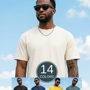 May include: A short-sleeved crew neck t-shirt in a solid cream color, worn with a silver chain necklace and black sunglasses. The image includes a circular graphic with the text 14 COLORS and four smaller thumbnails showing the shirt in black, navy, yellow, and green.