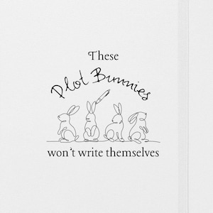 May include: White notebook with a black line drawing of four bunnies. One bunny is holding a pencil. The text reads "These Plot Bunnies won't write themselves."