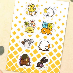 Könnte beinhalten: Ein Stickerbogen mit verschiedenen Cartoon-Charakteren in Gelb, Weiß und Braun. Die Aufkleber zeigen ein Küken, eine Katze, eine Ente mit Sushi, ein Eichhörnchen, ein weißes Wesen, ein braunes Wesen und ein schwarzes Kaninchen. Das Wort "OK" ist ebenfalls enthalten.