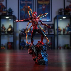 May include: A Spider-Man action figure in a red and black suit with four gold mechanical spider legs extending from the back. The figure is posed in a dynamic stance on a dark, jagged rock base, with one arm outstretched and a web-like effect.