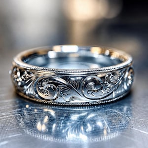 May include: A silver-toned metal ring featuring an intricate, deeply engraved scrollwork pattern across its outer surface. The band is bordered by fine, beaded milgrain detailing along both the top and bottom edges, creating a textured finish.