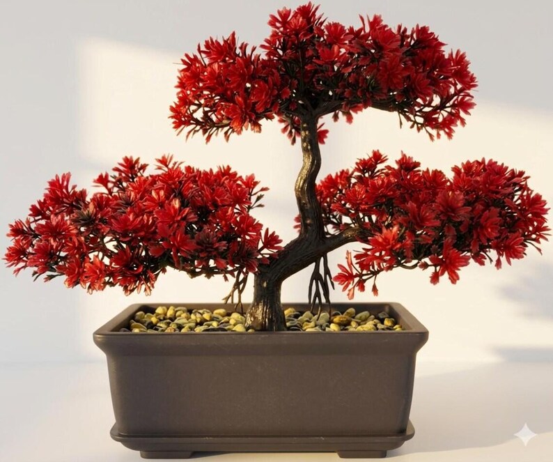 Op de afbeelding: Een kunstmatige bonsaiboom met levendig rood blad en een donkerbruine, getextureerde stam met zichtbare wortels. De boom is geplant in een rechthoekige, donkerbruine keramische pot gevuld met kleine, lichtgekleurde decoratieve steentjes.