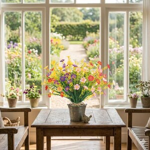 Pode incluir: Um balde de metal preenchido com um arranjo vibrante de flores silvestres artificiais em tons de amarelo, roxo, rosa, laranja e vermelho. O balde repousa sobre uma mesa de madeira, com caules e folhagens verdes que criam um arranjo denso.