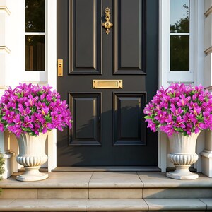 May include: Two off-white pedestal planters containing vibrant magenta flowers with green leaves, positioned on either side of a dark charcoal gray front door featuring a gold-colored metal door knocker and a rectangular mail slot.