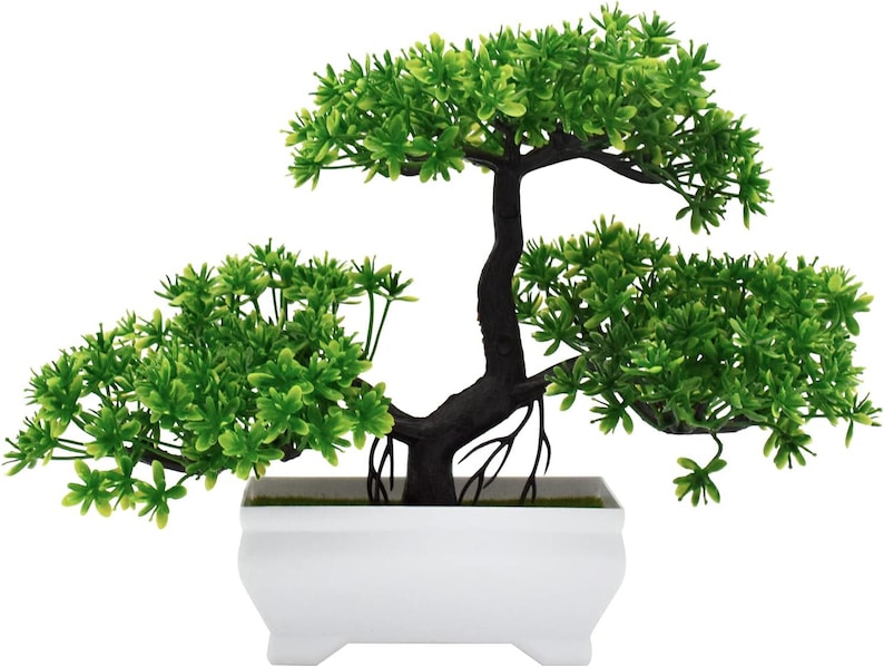 May include: A small artificial bonsai tree with vibrant green plastic foliage and a dark brown textured trunk. The tree is planted in a rectangular white plastic pot with four small feet at the base, creating a clean and simple decorative display.