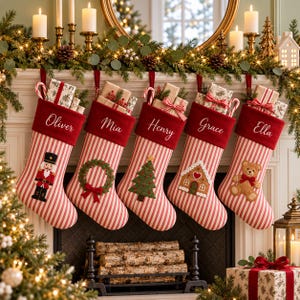 Puede incluir: Cinco calcetines navideños de rayas rojas y blancas con puños de terciopelo rojo, personalizados con los nombres Oliver, Mia, Henry, Grace y Ella. Incluyen apliques bordados de un cascanueces, corona, árbol, casa y un oso de peluche.